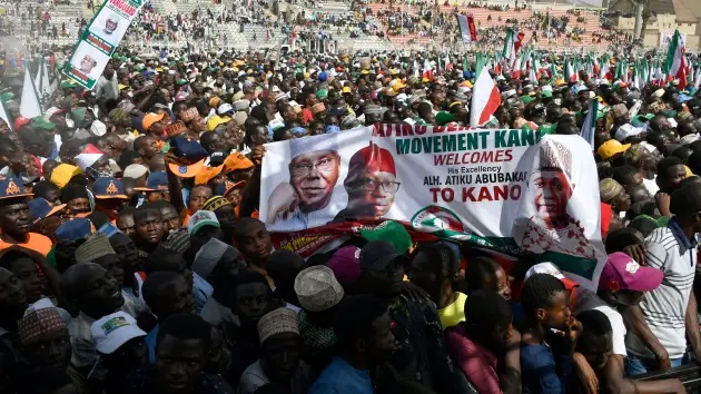 KANO, Nigérie – 9. února 2023: Příznivci nesou prapor kandidáta opoziční Lidové demokratické strany (PDP) Atiku Abubakara a kandidáta Ifeanyi Okowa během předvolebního shromáždění v Kano na severozápadě Nigérie