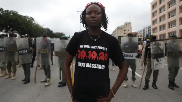 ABUJA, Nigérie - 20. října 2021: Mladá žena stojí před pořádkovými policisty během protestu na připomenutí ročního výročí EndSars, protestního hnutí proti policejní brutalitě u fontány Unity v Abuji.